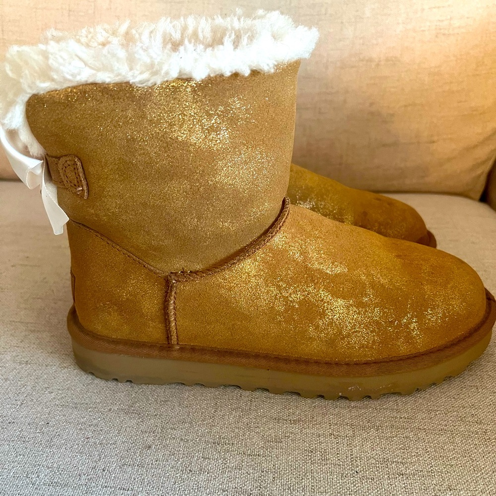 Gold glittery Uggs with white bows on the back